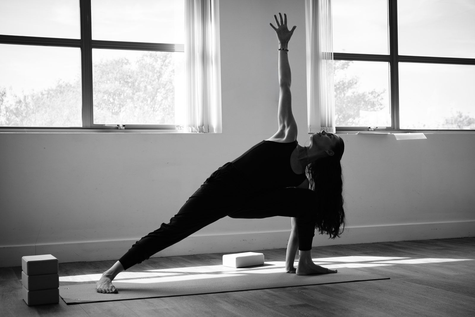 Holly in a wide standing pose, side body long, weight through both feet.